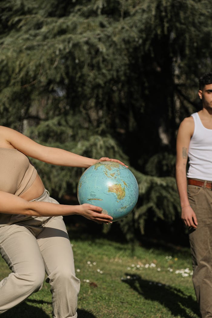 Two adults holding a globe, symbolizing global unity, in an outdoor park scene.